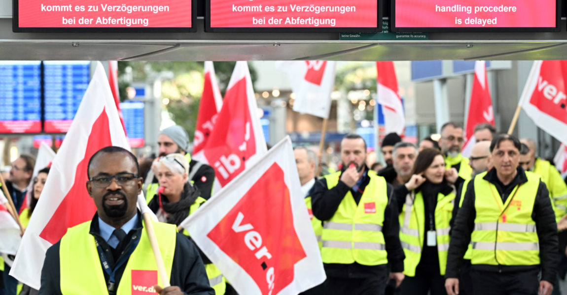  Streikende Flughafen-Mitarbeiter stehen mit Verdi-Flaggen im Terminal des Flughafens. Die Gewerkschaft Verdi hat ihre Mitglieder zu Warnstreiks an den nordrhein-westfälischen Flughäfen und im öffentlichen Dienst aufgerufen. 