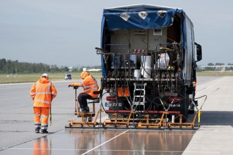 Eine spezielle Flüssig-Grundierung bringen Arbeiter mit einem Spezialfahrzeug auf der Landebahn Nordwest auf dem Flughafen in Frankfurt an.