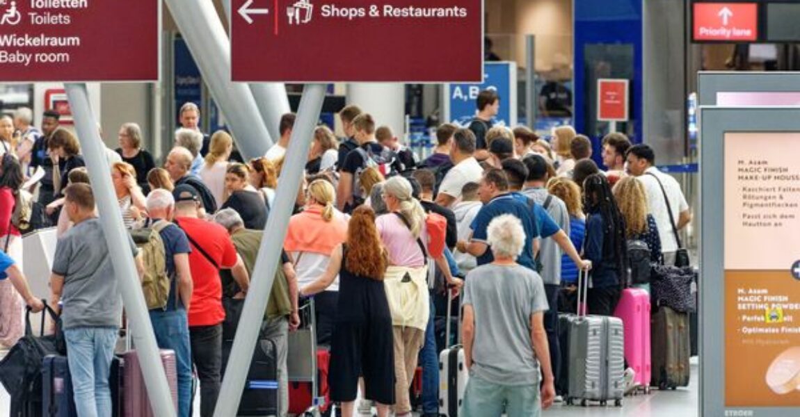 Reisende warten im Flughafen Düsseldorf vor Check-in-Schaltern.