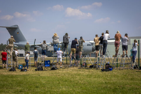 Air Defender 2023 lockt Planespotter an: Sie stehen an einem Zaun vor dem Fliegerhorst Wunstorf und fotografieren einen Airbus A400M der Luftwaffe.