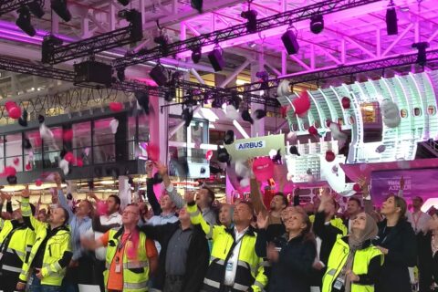 Jubelnd werfen die Airbus-Mitarbeiter ihre A321XLR-Mützen in die Luft – die neue Hamburger Strukturmontage des Erfolgsmodells ist eröffnet. Im Hintergrund ist der mit 